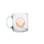 A glass mug with the words day dreamers club printed in an oval in pink and yellow colors in the middle of the glass.
