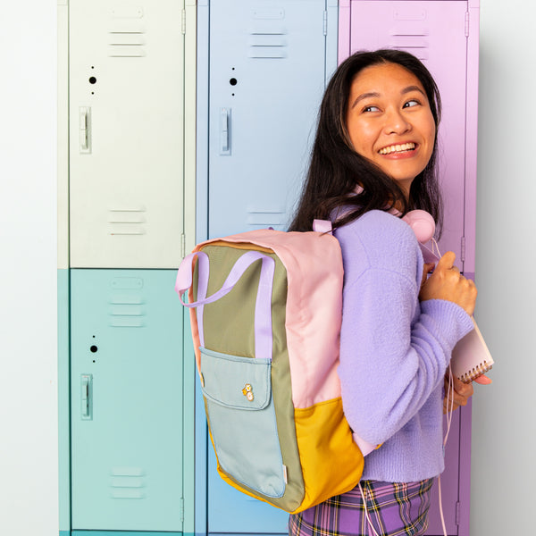 Girl wearing the multi color everyday backpack. Patel color lockers in the background. 