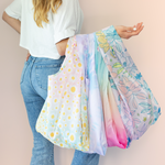 Lady holding large oopsie daisy, tie dye, and flock yeah twist and shouts. 