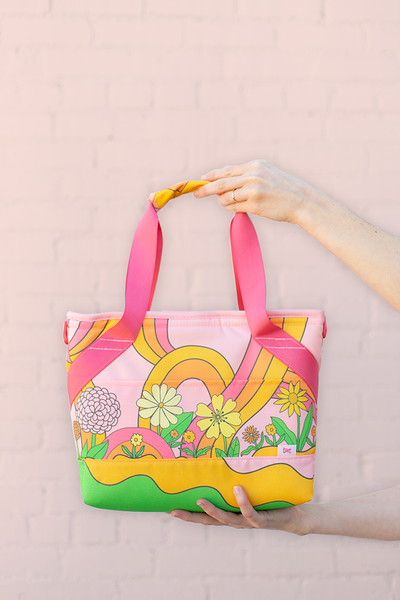 small pink soft sided cooler bag with flowers with girl holding handle