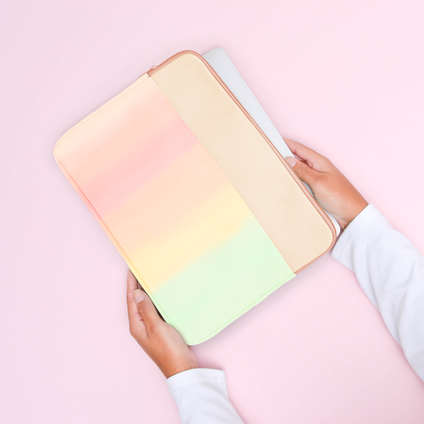 Hands holding a rainbow gradient laptop sleeve