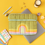 Puffy zippered pocket laptop sleeve on a Macbook along with other misc items. 