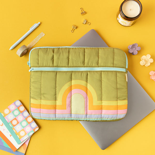 Puffy zippered pocket laptop sleeve on a Macbook along with other misc items. 