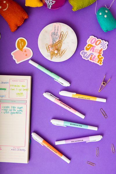 6 pastel highlighters displayed with TOOT Halloween Stickers and an Academic Planner. At the top of the picture is a Felt Multicolored Ghost Garland.