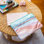 15in Zippered laptop sleeve with zippered front pocket and an open pocket in the back, laptop sleeve has water color stripes reminiscent of the sunset.A 15in laptop is wedge in the main caddy of the sleeve.