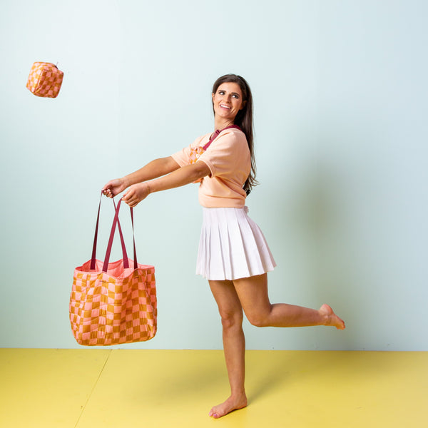 Model holding a pink puffy all day tote to catch a mod pouch