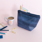 An indigo blue colored pouch that also has lighter blue marks. Shape of pouch is trapezoid-like.